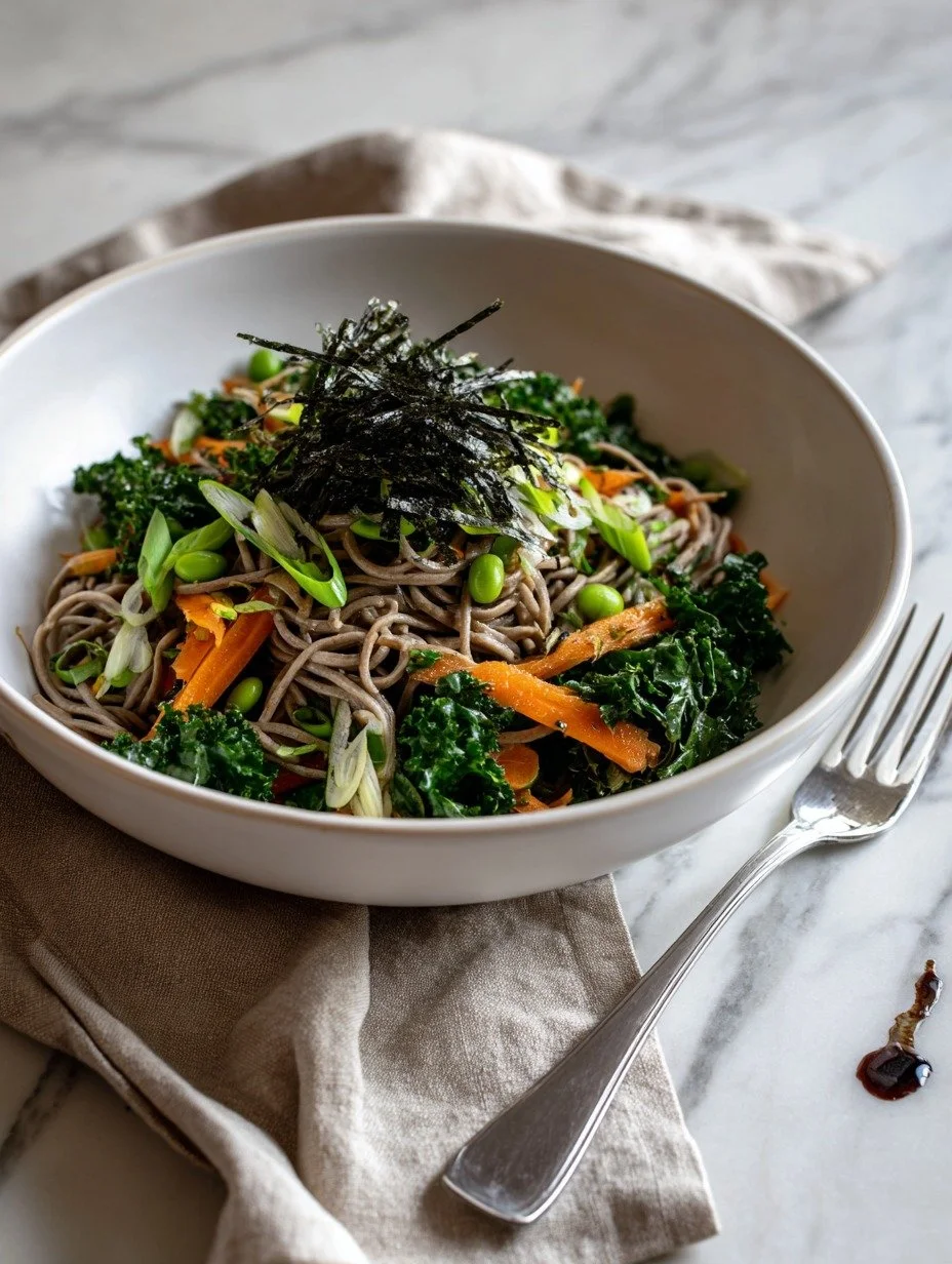 Bowl of soba noodle salad with kale, edamame, carrots and shredded nori on top