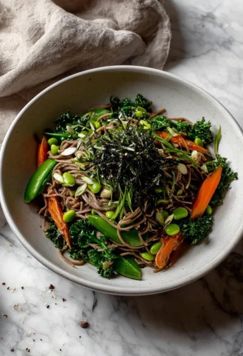 Overhead view of soba noodle salad showing sugarsnap peas, carrots, kale and sesame
