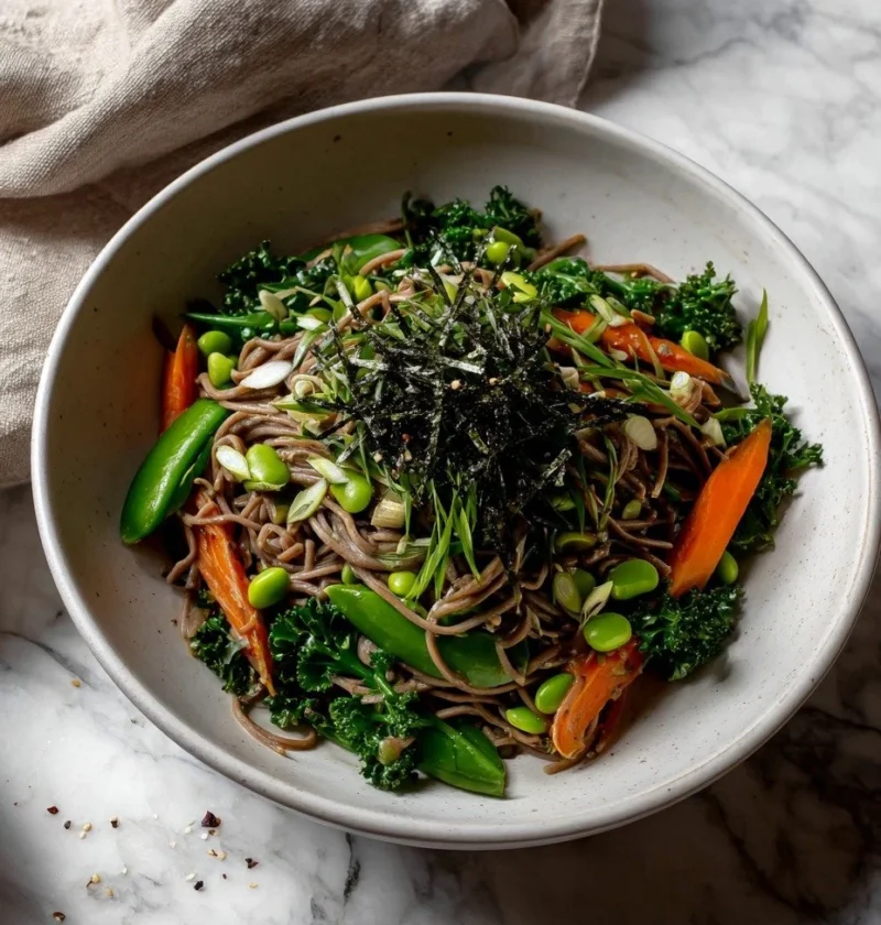 Overhead view of soba noodle salad showing sugarsnap peas, carrots, kale and sesame