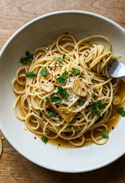 Gordon Ramsay aglio olio, spaghetti tossed with golden sliced garlic, chilli flakes, parsley and a glossy garlic oil sauce in a bowl