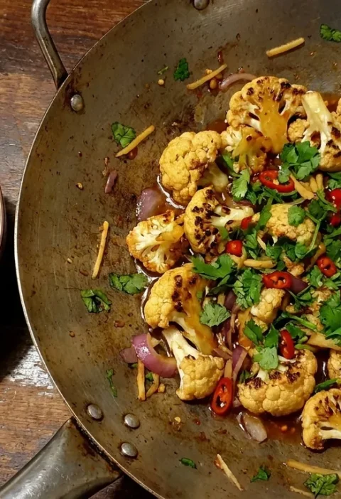 Gordon Ramsay bang bang cauliflower in a wok with charred florets, sweet chilli sauce, coriander, red chilli and ginger with rice
