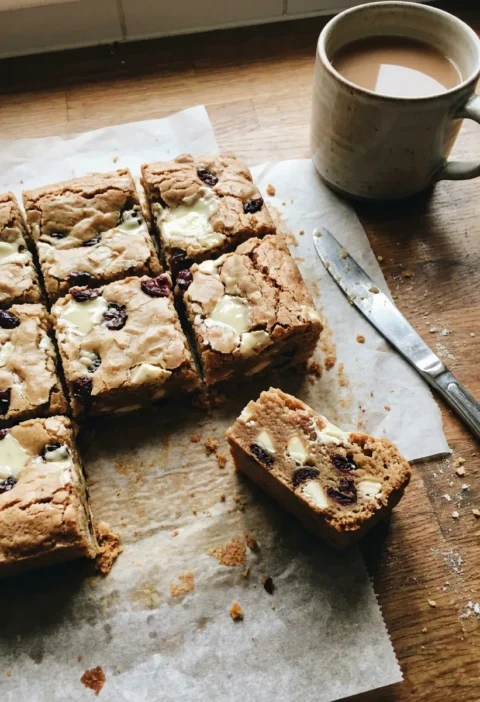 Gordon Ramsay blondies with white chocolate and cranberries on a wooden worktop