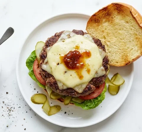 Gordon Ramsay BSK burger with thick beef patty, double melted Monterey Jack and Char Siu butter, lettuce, tomato and gherkins on a toasted brioche bun