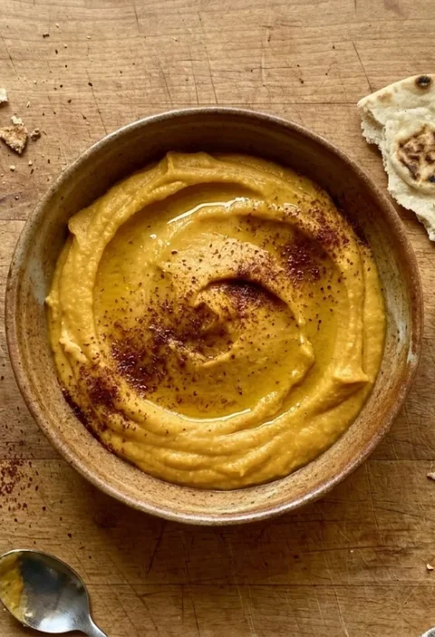 Gordon Ramsay butternut squash hummus with ras el hanout spice blend in a ceramic bowl with griddled pitta bread on a wood table