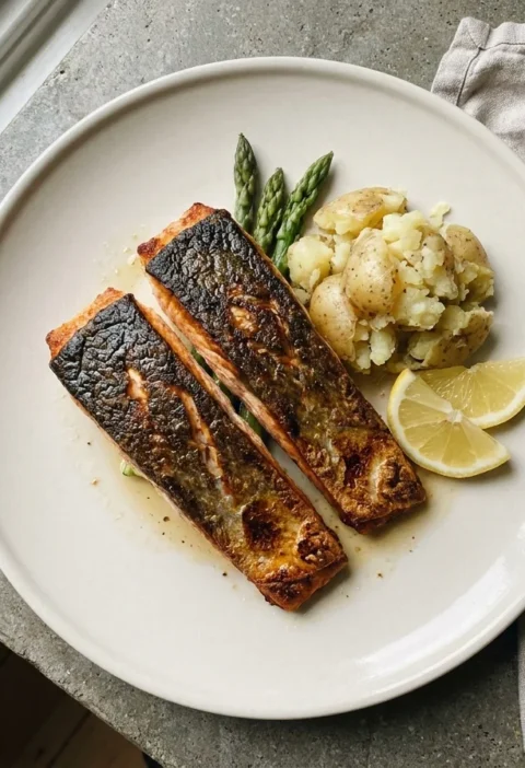 Gordon Ramsay crispy skin salmon, two pan-fried fillets skin-side up with crisp golden skin, crushed potatoes and lemon