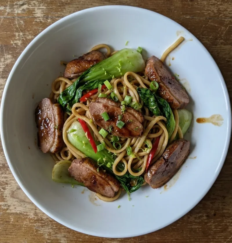 Gordon Ramsay duck stir fry with egg noodles, pak choi, red chilli and spring onions in a white bowl
