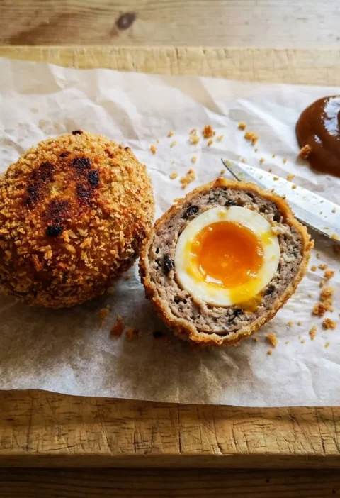 Gordon Ramsay scotch eggs cut in half showing jammy yolk and black pudding sausage meat with panko coating