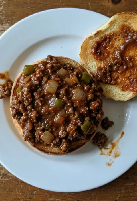 Gordon Ramsay sloppy joes, thick spiced beef mince in a sweet tangy tomato sauce piled into a toasted bun on a white plate