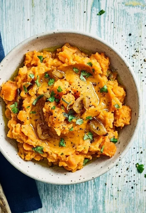 Gordon Ramsay sweet potato mash crushed with caramelized shallots coriander and sage in a speckled bowl