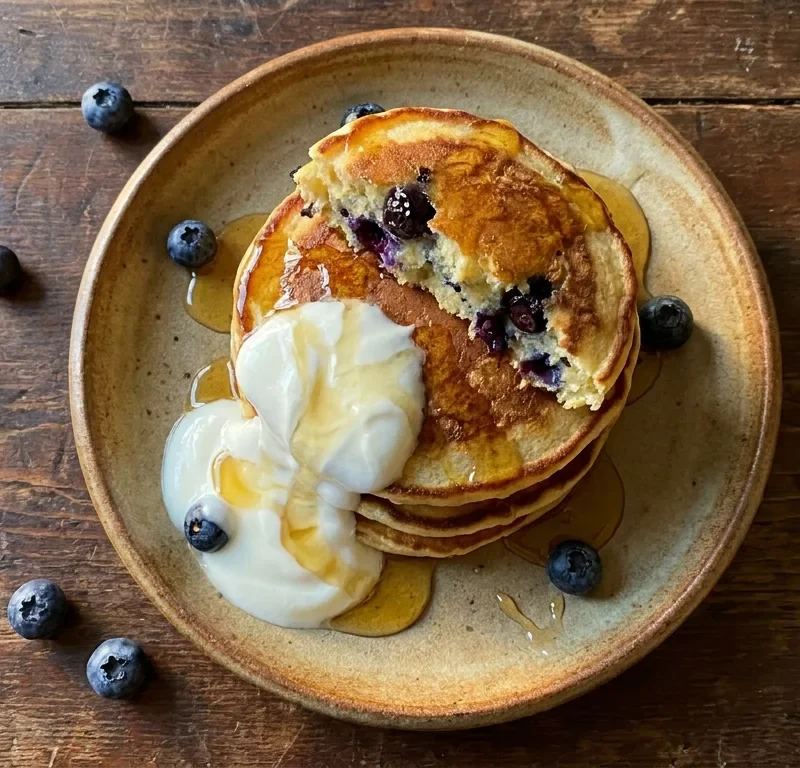 Gordon Ramsay blueberry ricotta pancakes with Greek yoghurt and honey on a ceramic plate