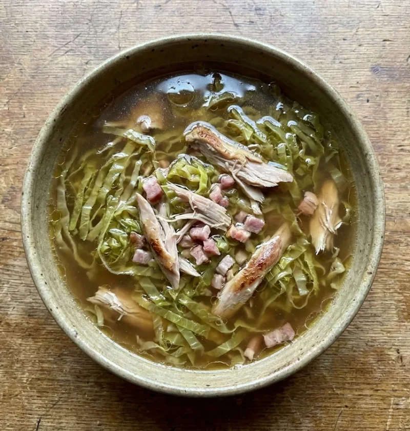 Gordon Ramsay cabbage soup with shredded Savoy cabbage and pulled rabbit meat in a clear brown broth