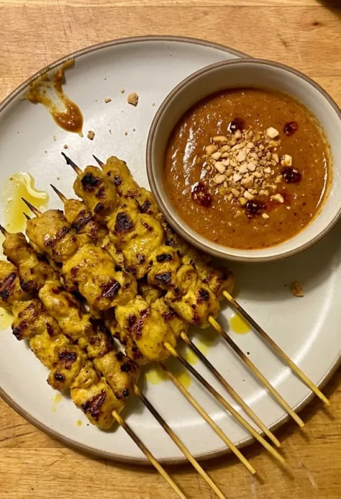 Gordon Ramsay chicken satay skewers, turmeric-marinated chicken with charred spots and a bowl of Malaysian peanut sauce