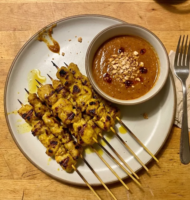 Gordon Ramsay chicken satay skewers, turmeric-marinated chicken with charred spots and a bowl of Malaysian peanut sauce