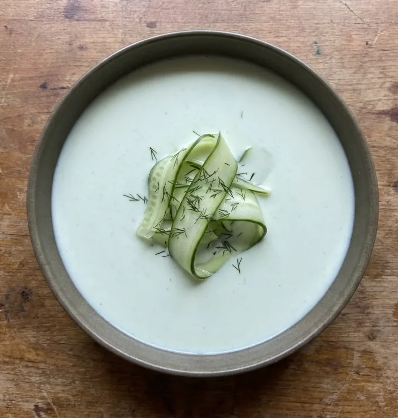 Gordon Ramsay chilled cucumber soup, pale and smooth in a dark bowl, topped with folded cucumber ribbons and dill fronds
