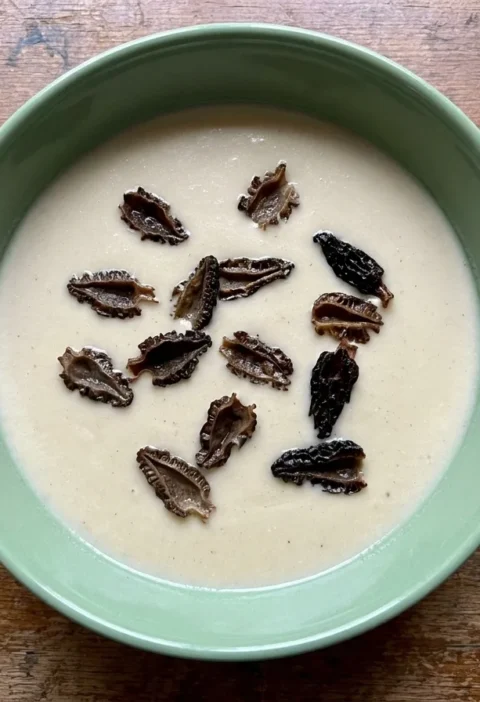 Gordon Ramsay Jerusalem artichoke soup blended smooth and pale beige, scattered with halved fried morels