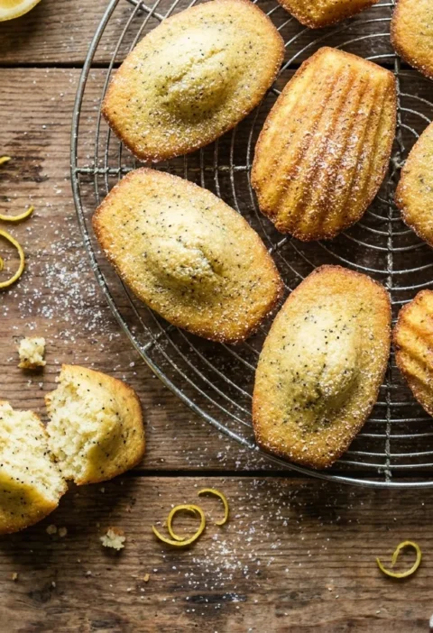 Gordon Ramsay lemon and poppy seed madeleines on a wire rack with lemon zest
