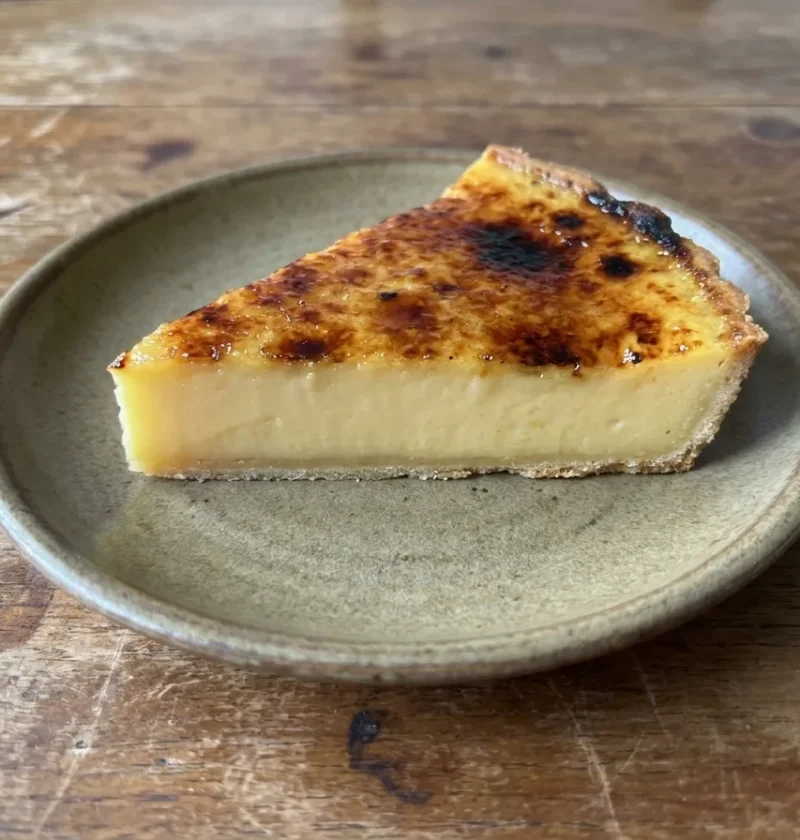 Gordon Ramsay orange and lemon tart sliced to show thin pastry, pale citrus custard and a torched sugar crust