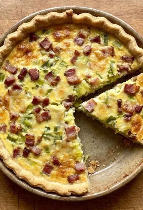Gordon Ramsay bacon and leek quiche with golden Gruyere top and shortcrust pastry in a ceramic dish