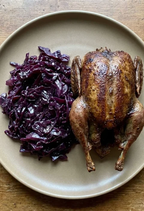 Gordon Ramsay roast pigeon browned whole and served breast up beside a pile of braised pickled red cabbage