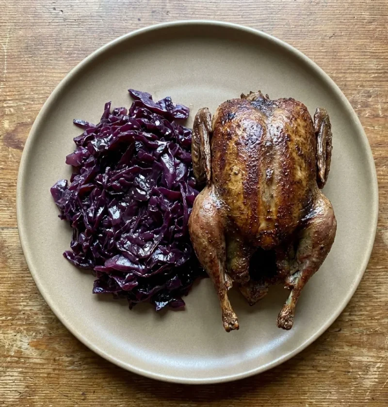 Gordon Ramsay roast pigeon browned whole and served breast up beside a pile of braised pickled red cabbage