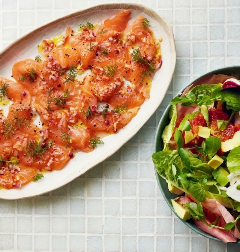 Gordon Ramsay salmon ceviche with thin raw salmon slices, red onion, pink peppercorns and fennel fronds beside a blood orange and avocado salad
