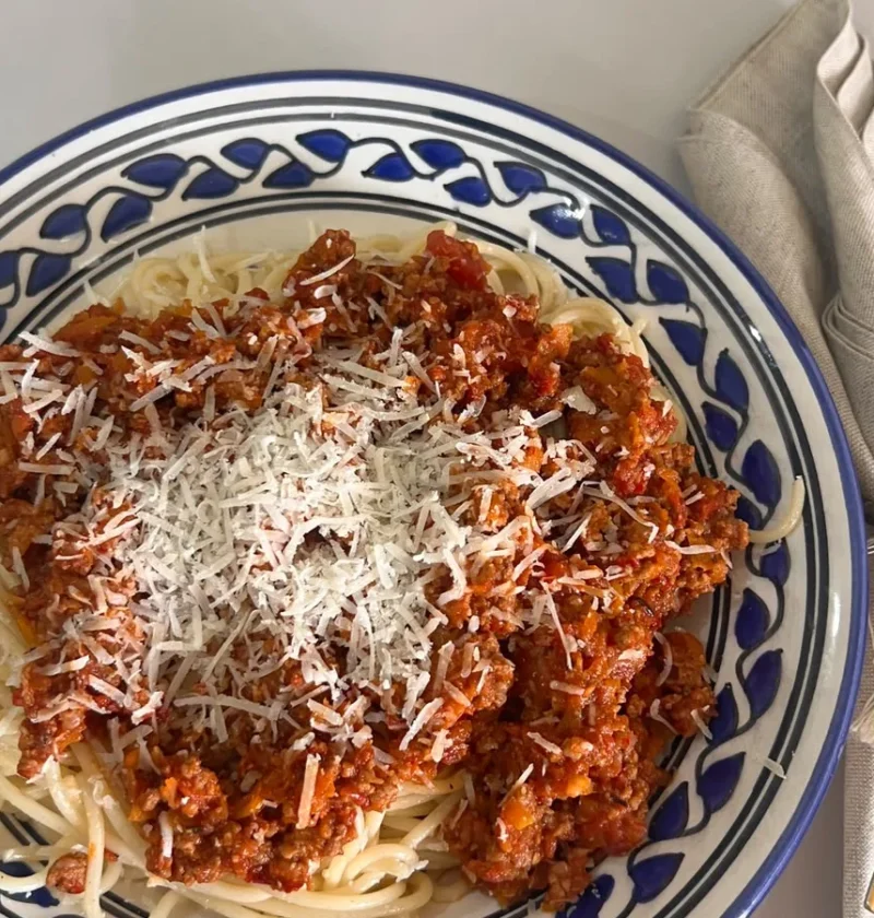 Gordon Ramsay spaghetti bolognese served in a blue patterned bowl, topped with grated Parmesan